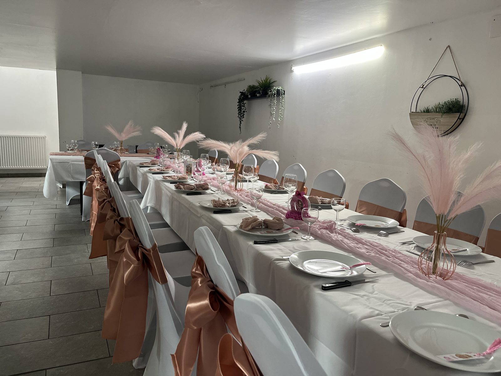 Salle Dionysos aménagée pour un baptême, table longue et centres de table plumes