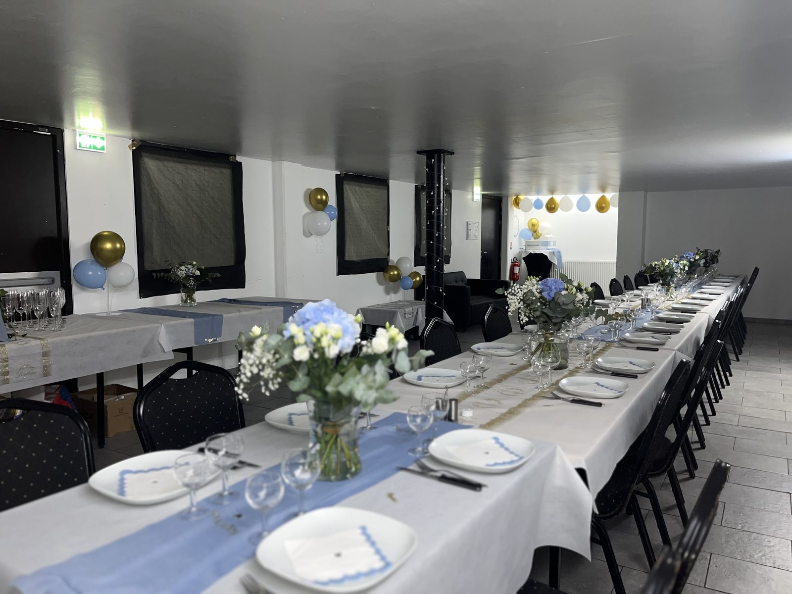 Table dressée bleu et or pour une réception de baptême, fleurs et vaisselle blanche